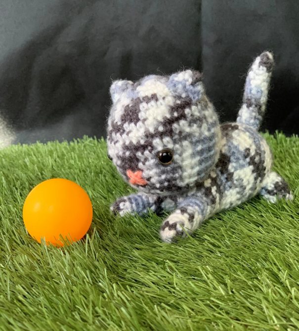 Chat gris au crochet jouant avec une balle orange