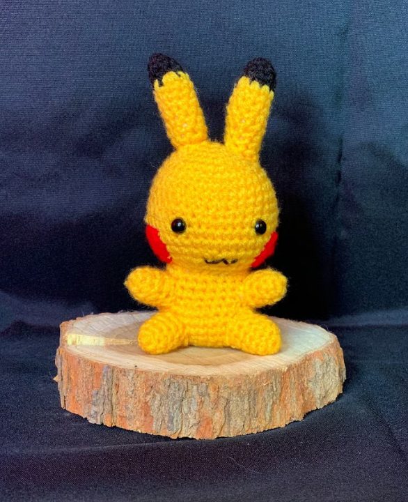 Pikachu au crochet jaune sur rondin de bois